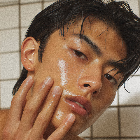 Person with hand on face against a tiled bathroom wall