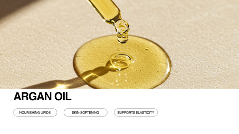 Close-up of a dropper releasing argan oil onto a smooth, light surface. Text at the bottom reads “ARGAN OIL” with icons for Nourishing Lipids, Skin-Softening, and Supports Elasticity.