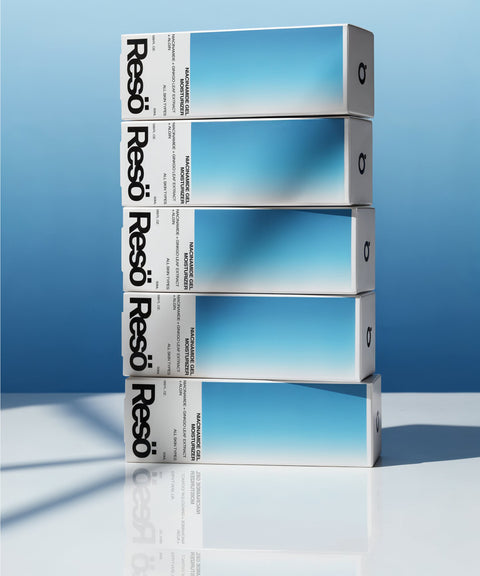 Five rectangular boxes with a gradient blue design and the brand name RESÖ, stacked diagonally on a reflective white surface against a blue background, highlight the Niacinamide Gel Moisturiser's shine-controlled hydration for sensitive skin.