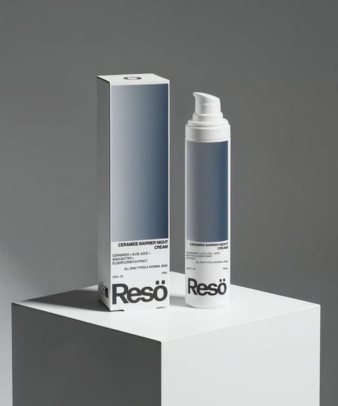 A sleek RESÖ Ceramide Barrier Night Cream bottle and box, both in minimalist blue-gray gradient, sit on a white pedestal. The cream is infused with ceramides and hyaluronic acid, set against a neutral gray background.