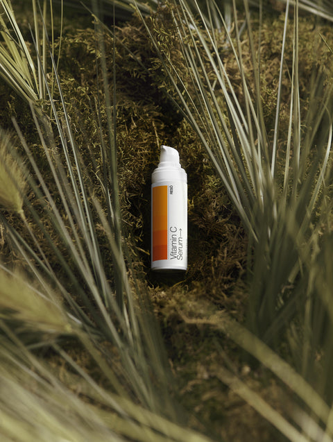 Vitamin C serum bottle on a grassy background