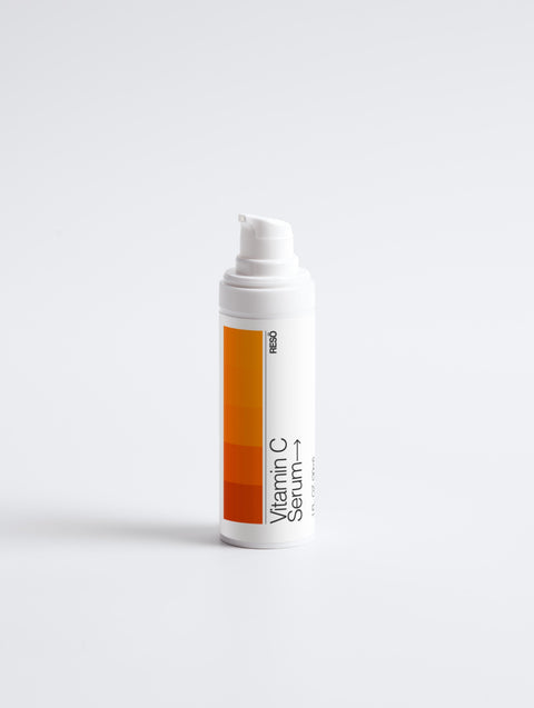 Vitamin C serum bottle with orange label on a white background