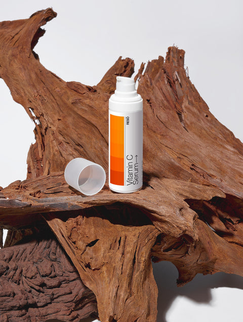 Vitamin C serum bottle on a wooden surface with a white background