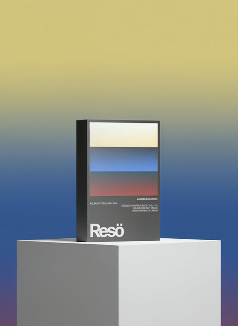 A rectangular Barrier Boost Box by RESÖ sits on a white pedestal, set against a yellow, blue, and beige gradient background that complements the box’s abstract design—ideal for highlighting their hydration gel.