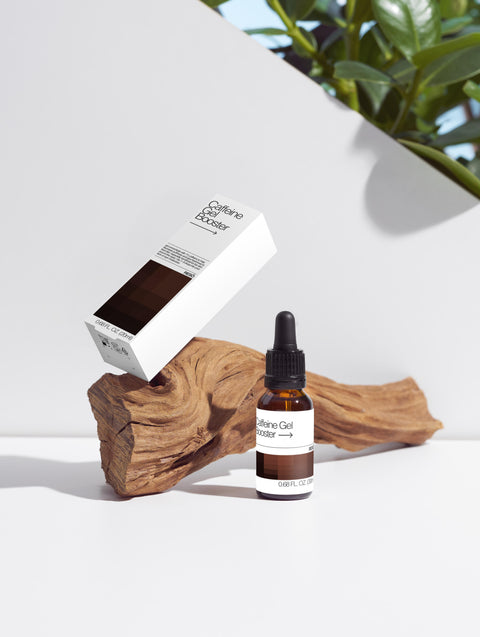 Bottle and box of a skincare product on a wooden block with a white background