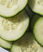 Close-up of overlapping cucumber slices, their fresh, juicy texture evoking the hydration and softness you feel after applying the 5% Urea + 2% Panthenol Body Cream. Bright light highlights their crispness, symbolizing skincare refreshment.