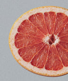 A close-up of Hand & Body Wash, Grapefruit features bright red grapefruit flesh and a yellow rind against a light gray background, capturing the juicy segments and refreshing grapefruit essence of the product.