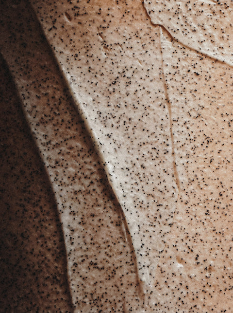 Close-up of an abstract, organic pattern in beige and brown tones, with dark speckles and wavy lines, evoking the mineral-rich texture of Icelandic Volcano Face & Body Scrub for deep cleansing.